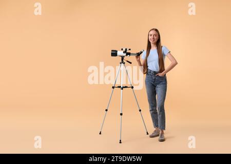 Glücklicher Astronom mit Teleskop auf beigefarbenem Hintergrund, Platz für Text Stockfoto