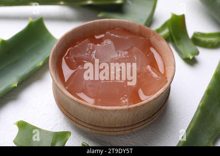 Aloe Vera Gel in Schüssel und Pflanzenscheiben auf weißem, strukturiertem Hintergrund, Nahaufnahme Stockfoto