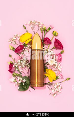 Pazifismus und Gewaltlosigkeit. Große Kugel und ein Haufen verschiedener Blumen vor pastellrosa Hintergrund. Stockfoto