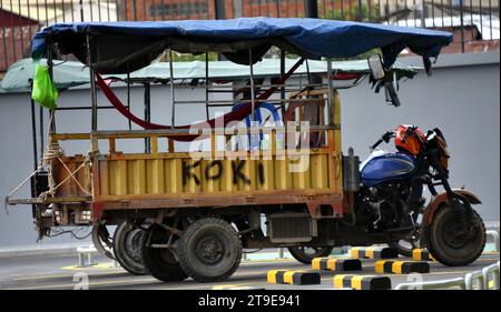 Großes Tuk Tuk, gezogen von einem Motorrad, ein sehr häufiges Taxi in Phnom Penh Kambodscha, Südostasien, Straßenszene, Straße, Fahrzeug, songthaew ist ein Personenkraftwagen hier und in Thailand, Laos, Vietnam und Myanmar, der von einem Pick-up oder einem größeren Lkw angepasst und als gemeinsames Taxi oder Bus genutzt wird Stockfoto