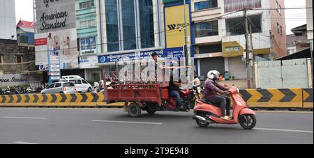 Großes Tuk Tuk, gezogen von einem Motorrad, ein sehr häufiges Taxi in Phnom Penh Kambodscha, Südostasien, Straßenszene, Straße, Fahrzeug, songthaew ist ein Personenkraftwagen hier und in Thailand, Laos, Vietnam und Myanmar, der von einem Pick-up oder einem größeren Lkw angepasst und als gemeinsames Taxi oder Bus genutzt wird Stockfoto