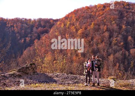 Junge Familie mit Baby und Kleinkind, die im Wald wandern Stockfoto