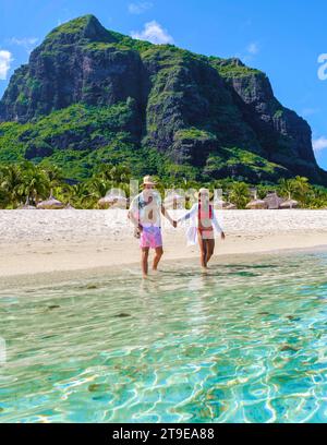Mann und Frau an einem tropischen Strand auf Mauritius, ein Paar auf einem Flitterwochenurlaub in Mauritius Le Morne Beach mit Le Morne Mountain im Hintergrund Stockfoto