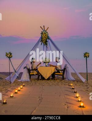 Romantisches Abendessen am Strand in Phuket Thailand, Paar Mann und Frau mittleren Alters asiatische Frau und europäischer Mann beim Abendessen am Strand in Thailand während des Sonnenuntergangs. Stockfoto