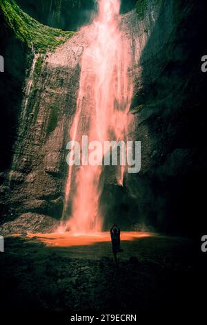 Ein Yoga-Mann vor dem wunderschönen Blick auf den Madakaripura Wasserfall. Der Madakaripura Wasserfall ist der höchste Wasserfall in Java Stockfoto