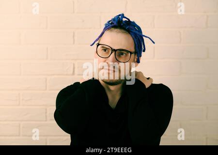 Ein Mann mit leuchtenden lila Dreadlocks und einem eleganten schwarzen Hoodie. Stockfoto