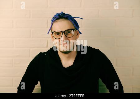 Ein Mann mit leuchtenden lila Dreadlocks und einem eleganten schwarzen Hoodie. Stockfoto