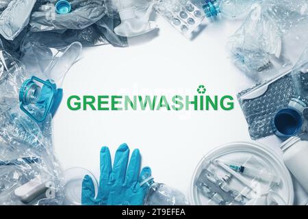 Stapel Kunststoffabfälle und Greenwashing-Schriftzug. Konzept von Greenscamming, Green PR und Betrugsmarketing. Stockfoto