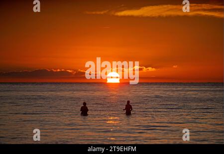 Swansea, Großbritannien. November 2023. Schwimmer beobachten den Sonnenaufgang in der Langland Bay nahe Swansea, während die Lufttemperatur heute Morgen schwer über dem Gefrierpunkt steigt. Quelle: Phil Rees/Alamy Live News Stockfoto