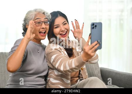 Überglückte Erwachsene Tochter und ältere Mutter machen zu Hause Selfie mit Smartphone Stockfoto