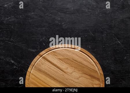 Rundes Schneidebrett aus Holz für Pizza, dunkler Hintergrund von oben, mit Platz zum Kopieren von Text. Stockfoto