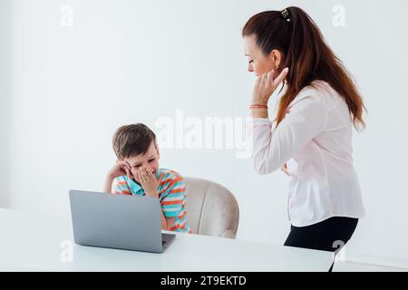 Frau, die den Jungen auf Laptop in der Schule unterrichtet Stockfoto