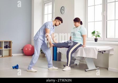 Arzt, der die Beinmuskeln einer fetten Frau massiert, die sich in der Klinik einer physiotherapeutischen Behandlung unterzieht Stockfoto