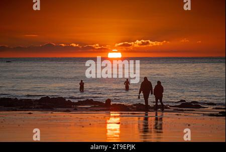 Swansea, Großbritannien. November 2023. Schwimmer beobachten den Sonnenaufgang in der Langland Bay nahe Swansea, während die Lufttemperatur heute Morgen schwer über dem Gefrierpunkt steigt. Quelle: Phil Rees/Alamy Live News Stockfoto