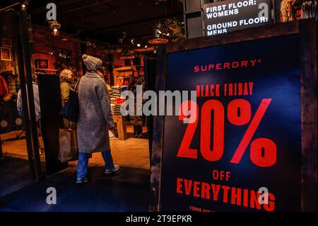 Amsterdam, Niederlande. November 2023. Eine Frau betritt einen Kleiderladen "Superdry" mit Black Friday Deals. In Amsterdam sind die Geschäfte mit Black Friday-Angeboten fertig, und die Schaufenster sind mit Werbebanner verziert, um während des Black Friday Menschen anzulocken. Vor allem jüngere Menschen warten auf den Ermäßigungstag nach Amerikas Thanksgiving, um Dinge zu kaufen. (Foto: Ana Fernandez/SOPA Images/SIPA USA) Credit: SIPA USA/Alamy Live News Stockfoto