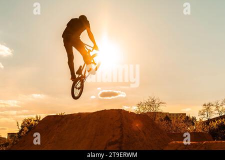 Biker-Silhouette beim Sprung. Mann auf bmx-Fahrrad gegen Sonnenschein. Hoher BMX-Sprung. Stockfoto