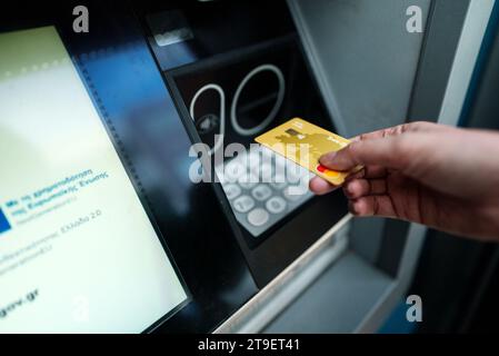 Athen, Griechenland - 14.06.2023: Frau benutzt einen griechischen Geldautomaten, um Geld abzuheben. Redaktionelle Verwendung. Stockfoto