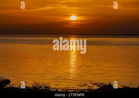 Ein farbenfroher Sonnenuntergang reflektiert sich auf einem ruhigen und ruhigen Bristol Kanal Stockfoto