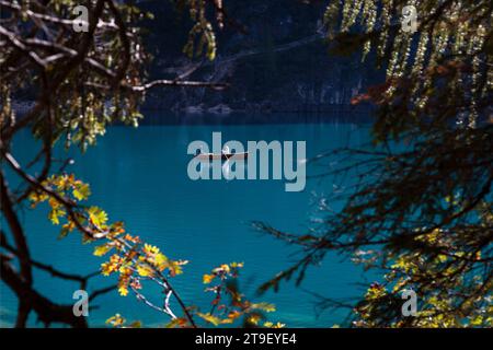 Romantischer Blick auf das Boot auf dem wunderschönen blauen See, eingerahmt von Bäumen in Herzform. Paare auf dem Holzboot auf dem Pragser See in den Dolomiten Stockfoto