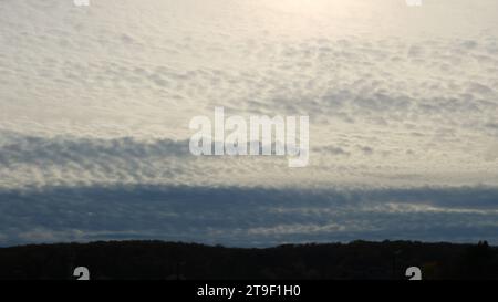 Cirrostratus Wolken in einem hellen Himmel über einem dunklen bewaldeten Berg, Sonnenuntergang bewölkter Himmel am Abend in einer hügeligen Gegend, sanfter Sonnenuntergang in einem hohen Himmel Stockfoto