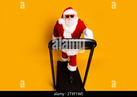 Foto in voller Länge des energetischen, fröhlichen Rentners santa claus, der isoliert auf gelbem Hintergrund abnimmt Stockfoto