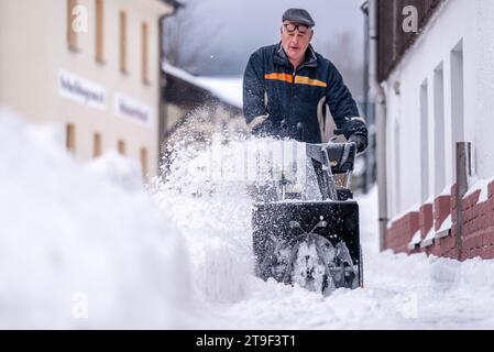 Oberwiesenthal, Deutschland. November 2023. Ein Mann räumt den Gehweg mit einem Schneefräse. In der Nacht gab es Neuschnee im Erzgebirge. Kristin Schmidt/dpa/Alamy Live News Stockfoto