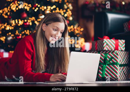 Nahaufnahme Porträt eines niedlichen Teenagers, der einen Brief für den weihnachtsmann mit Laptop in der Nähe von Geschenkboxen schreibt, Weihnachtswünsche isoliert zu Hause Stockfoto