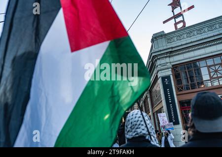 Seattle, Usa. November 2023. Ein Demonstrant hält während der Demonstration eine palästinensische Flagge vor Starbucks. Eine Versammlung pro-palästinensischer Anhänger fand im First Starbucks Reserve Roastery in Seattles lebhaftem Capitol Hill statt. Bei der Veranstaltung, die durch Demonstrationen gekennzeichnet war, wurden verschiedene Schilder und Botschaften deutlich sichtbar angezeigt. Unter den zahlreichen Schildern, die von den Demonstranten getragen wurden, lautete eines: "Steht mit Palästina! Beende die Besatzung jetzt!“ Während andere verkündeten: "Palästina wird frei sein!" Quelle: SOPA Images Limited/Alamy Live News Stockfoto