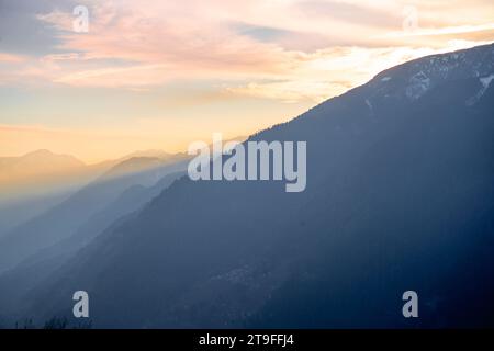 Ruhige, friedliche Aussicht auf die himalaya Berge vom Hamta Dorf Trek mit Farbtönen bei Sonnenaufgang der Abenddämmerung und Sonnenstrahlen, die zwischen den Bergen in Manali vorbeiziehen Stockfoto