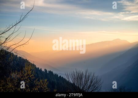 Ruhige, friedliche Aussicht auf die himalaya Berge vom Hamta Dorf Trek mit Farbtönen bei Sonnenaufgang der Abenddämmerung und Sonnenstrahlen, die zwischen den Bergen in Manali vorbeiziehen Stockfoto