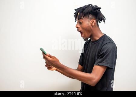 Foto eines jungen Schwarzen auf Dreadlocks, der eine Nachricht auf dem Handy sendet. Glücklicher afroamerikanischer Mann mit Smartphone, Spaß beim Online-Chatten, Messagi Stockfoto