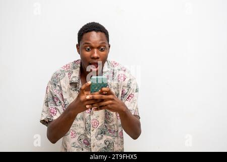 Porträt eines fröhlichen, jungen Schwarzen, der eine Nachricht per Handy sendet. Glücklicher afroamerikanischer Mann mit Smartphone, der gerne online chattet, Nachrichten schickt Stockfoto