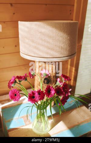 Hellrosa Gerbera-Blüten in einer Glasvase auf dem Beistelltisch Stockfoto