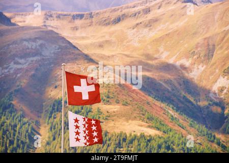 Schweizer Flagge und Flagge des Kantons Wallis gegen schweizer Alpenberg Stockfoto