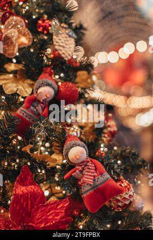 Weiche Schneemannfiguren hängen an einem Weihnachtsbaum mit goldenen Lichtern. Stockfoto