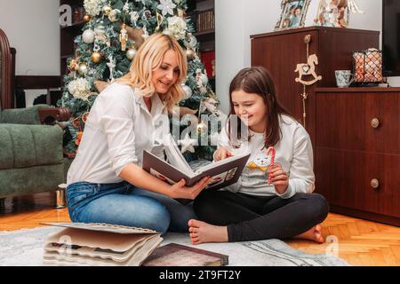 Mutter und Tochter sehen Fotos in den Fotoalben neben einem Weihnachtsbaum Stockfoto