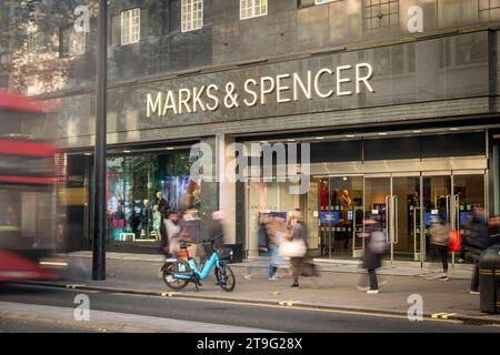 LONDON – 23. NOVEMBER 2023: Marks and Spencer Store and Motion verschwimmen die Käufer in der Oxford Street, einem Wahrzeichen des Einzelhandels Stockfoto