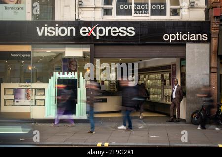 LONDON – 23. NOVEMBER 2023: Vision Express Optiker speichern und verschwommene Käufer in der Oxford Street, einem Wahrzeichen des Einzelhandels Stockfoto