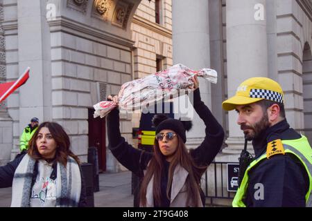 London, Großbritannien. November 2023. Polizisten halten eine Frau fest, weil sie ein Bild eines toten Kindes aus Laken in der Hand hält. Tausende von Menschen marschierten erneut in Zentral-London in Solidarität mit Palästina, während der Krieg zwischen Israel und der Hamas andauert. Quelle: Vuk Valcic/Alamy Live News Stockfoto