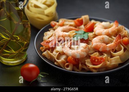 Fettuccine Nudeln mit Garnelen und Zutaten - Tomaten, rohe Nudeln, Olivenöl, selektiver Fokus. Stockfoto