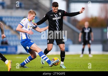 Zach Mitchell von Colchester United kämpft um den Ball mit Barrows Jamie Proctor während des Spiels der Sky Bet League Two im JobServe Community Stadium in Colchester. Bilddatum: Samstag, 25. November 2023. Stockfoto