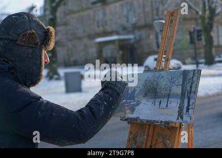 Ein Künstler, der eine Staffelei aus Holz verwendet, um eine Leinwand zu stützen, während er eine Szene einer urbanen Winterlandschaft in Harrogate, Yorkshire, Großbritannien, malt. Stockfoto