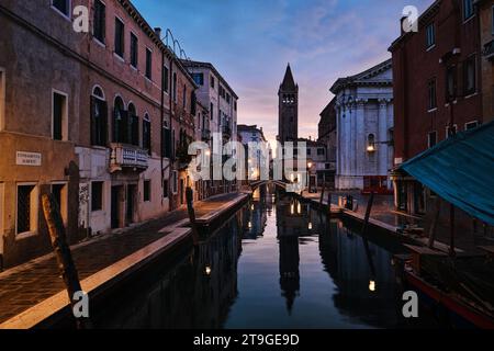 Venedig, Italien - 9. November 2023: Glockenturm der Chiesa di San Barnaba und schmaler Kanal in Venedig bei Sonnenaufgang Stockfoto