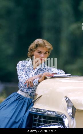 1950er Jahre: Eine nicht identifizierte Modell stellt in einem blauen Kleid, während auf der Vorderseite eines Auto ca. 50er sitzen. (Foto von Hy Peskin) Stockfoto