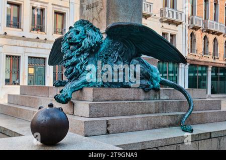 Venedig, Italien - 9. November 2023: Eine große Bronzeskulptur eines geflügelten Löwen liegt am Fuß der Statue von Daniele Manin. Skulptur von Luigi Borro im Jahre 1875 Stockfoto