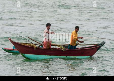 Zwei einheimische Fischer in einem Katamaranboot benutzen früh am Morgen in Mirissa Angelruten Stockfoto