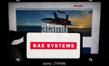 Person mit Smartphone und Logo des britischen Luft- und Raumfahrtunternehmens BAE Systems plc vor der Website. Schwerpunkt auf dem Display des Telefons. Stockfoto