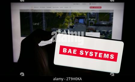 Person, die ein Mobiltelefon mit dem Logo des britischen Luft- und Raumfahrtunternehmens BAE Systems plc vor der Business-Website hält. Schwerpunkt auf dem Display des Telefons. Stockfoto