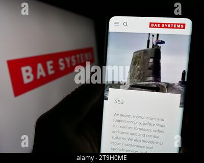 Person mit Mobiltelefon mit Website des britischen Luft- und Raumfahrt- und Verteidigungsunternehmens BAE Systems plc mit Logo. Konzentrieren Sie sich auf die Mitte des Telefondisplays. Stockfoto