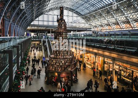 London, Großbritannien. November 2023. Wie es heute eine jährliche Tradition ist, zeigt die St. Pancras International Station wieder einmal einen ungewöhnlichen Weihnachtsbaum. In diesem Jahr haben sie in Zusammenarbeit mit Hatchards, dem ältesten Buchladen Großbritanniens, eine 12 Meter hohe Baumtreppe mit 270 Bücherregalen und fast 4.000 Büchern errichtet. Die Ecken und Nischen erweisen sich als beliebt bei Reisenden, die sich ausruhen oder eine Weile lesen möchten. Quelle: Imageplotter/Alamy Live News Stockfoto